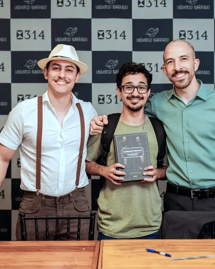 Professores posando com um leitor e o livro Lições de Cálculo na noite de autógrafos